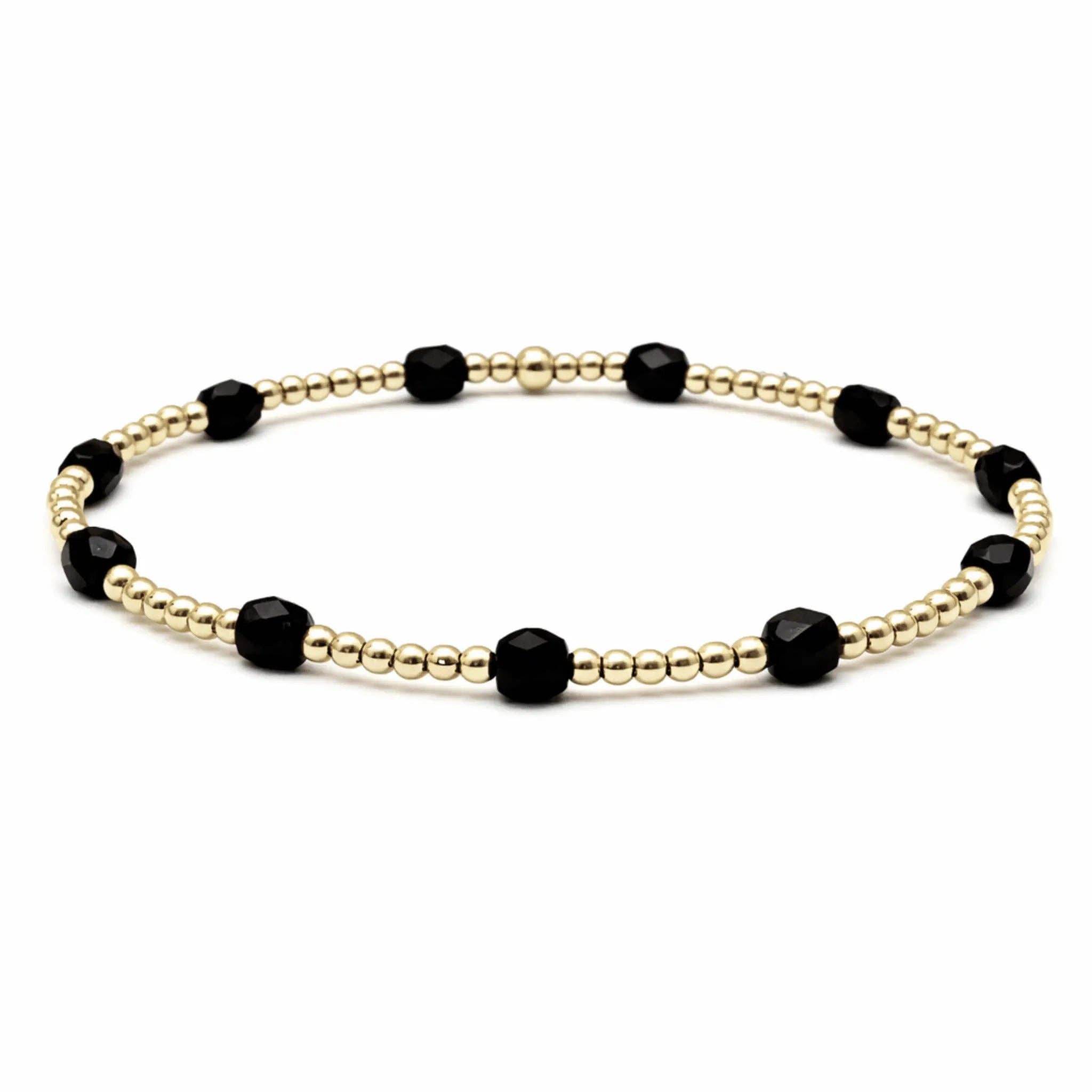 Bracelet with black beads and gold beaded chain on a white background
