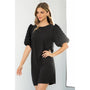 Woman wearing a black dress with puff sleeves against a white background