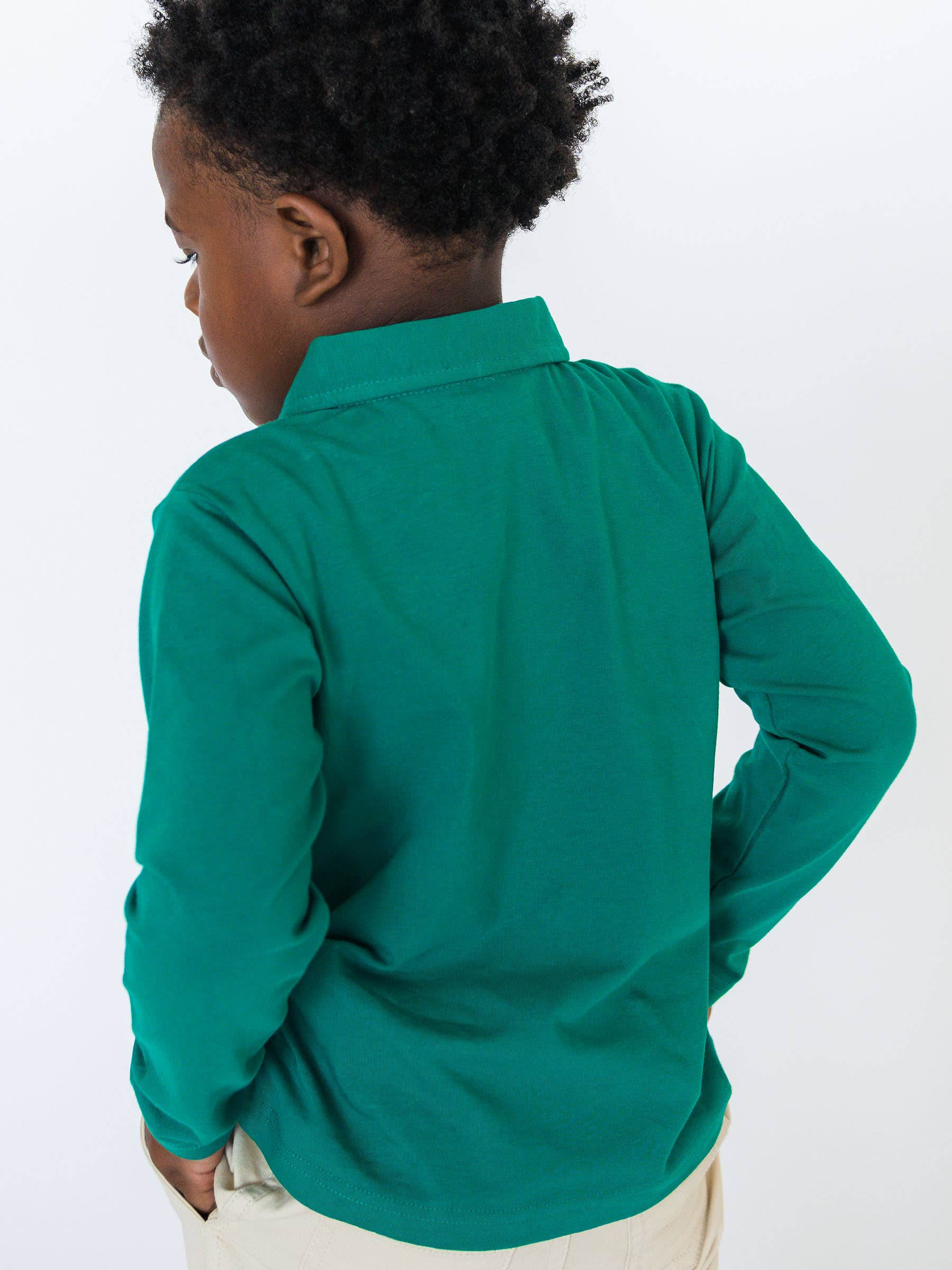 Child wearing a green long-sleeve shirt on a white background