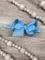 Blue bow hair accessory on a wooden surface with gray beads