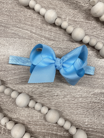 Blue bow hair accessory on a wooden surface with gray beads