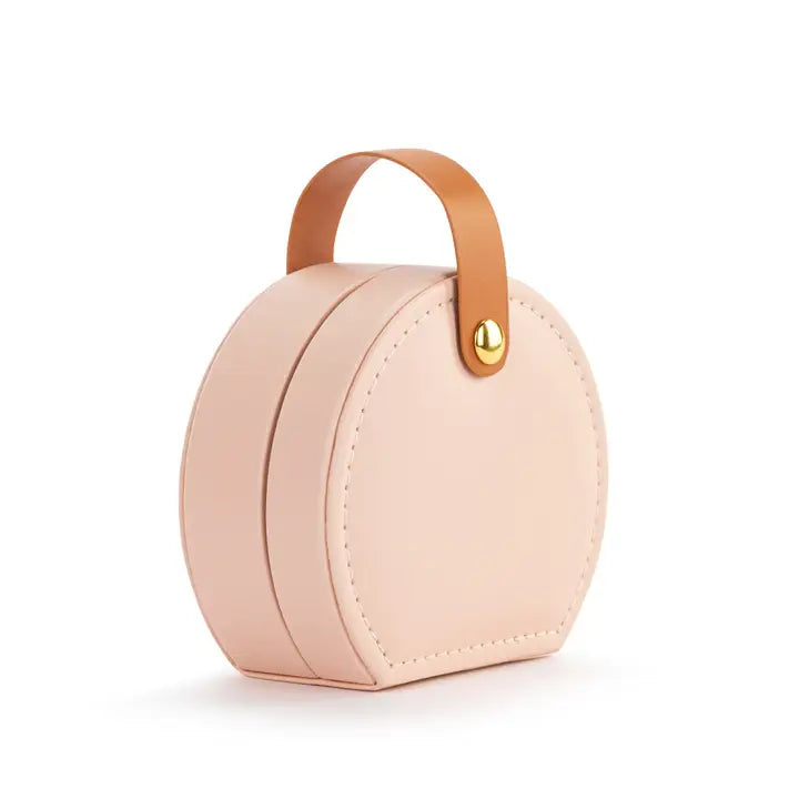 Small round pink purse with a tan handle on a white background