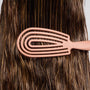 Person using a pink wide-tooth comb on their brown hair.