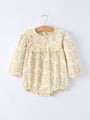 Baby romper with lace details on a hanger against a white background