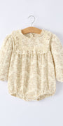 Baby romper with lace details on a hanger against a white background