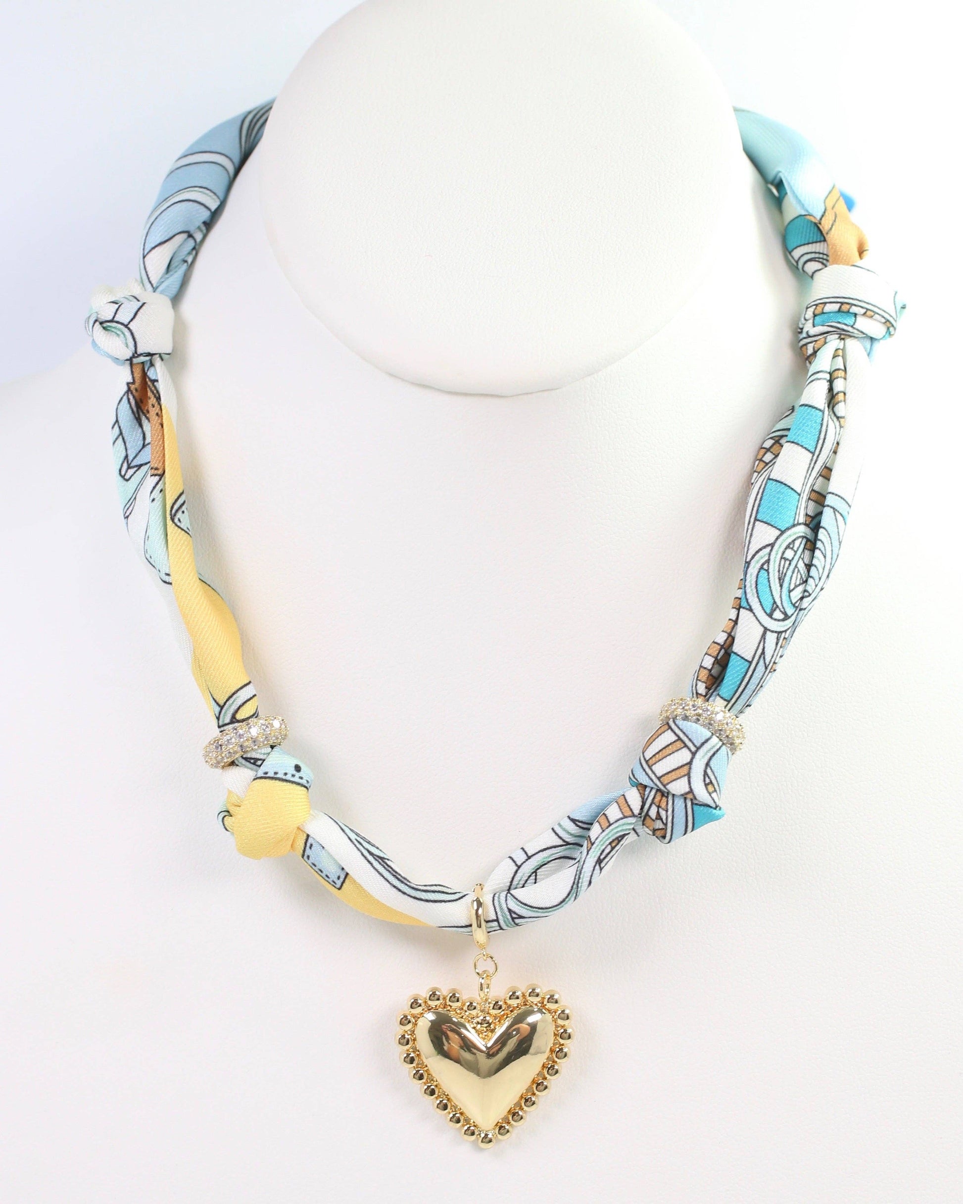 Necklace with heart pendant and colorful fabric wrap on a white background