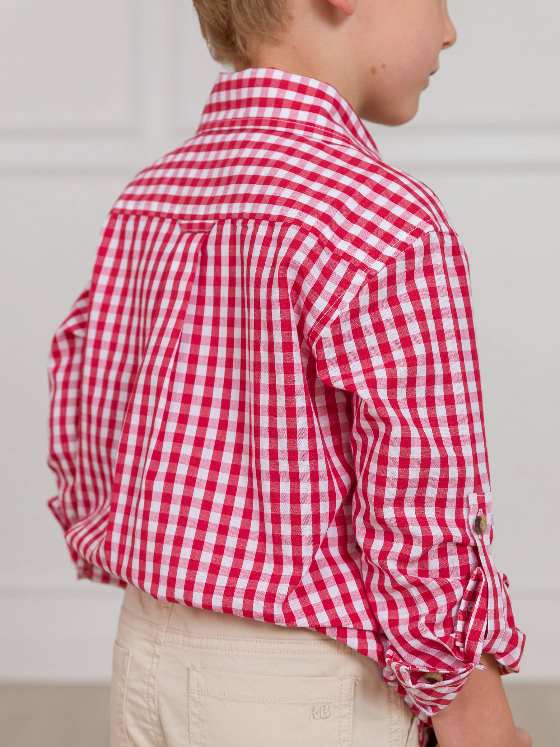 Child wearing a red and white checkered shirt against a plain background