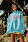 Woman wearing a light blue hoodie with 'Lolly Gag' text, standing outdoors.