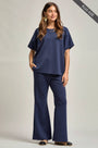Woman wearing a navy blue outfit with wide-leg pants on a plain background