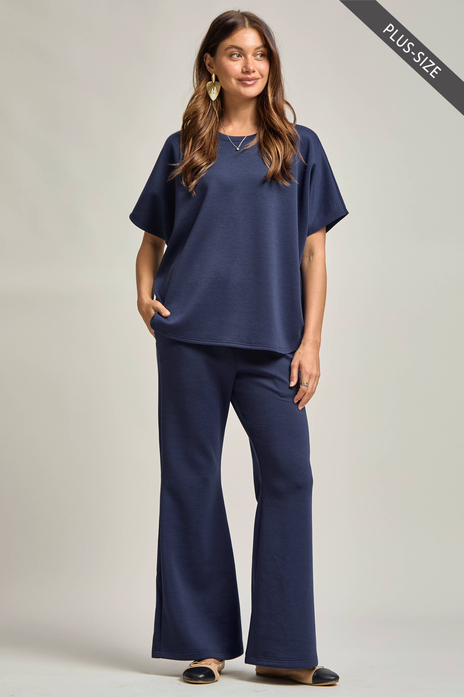 Woman wearing a navy blue outfit with wide-leg pants on a plain background