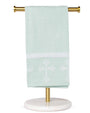 Light green towel with white cross design on a gold towel rack against a white background