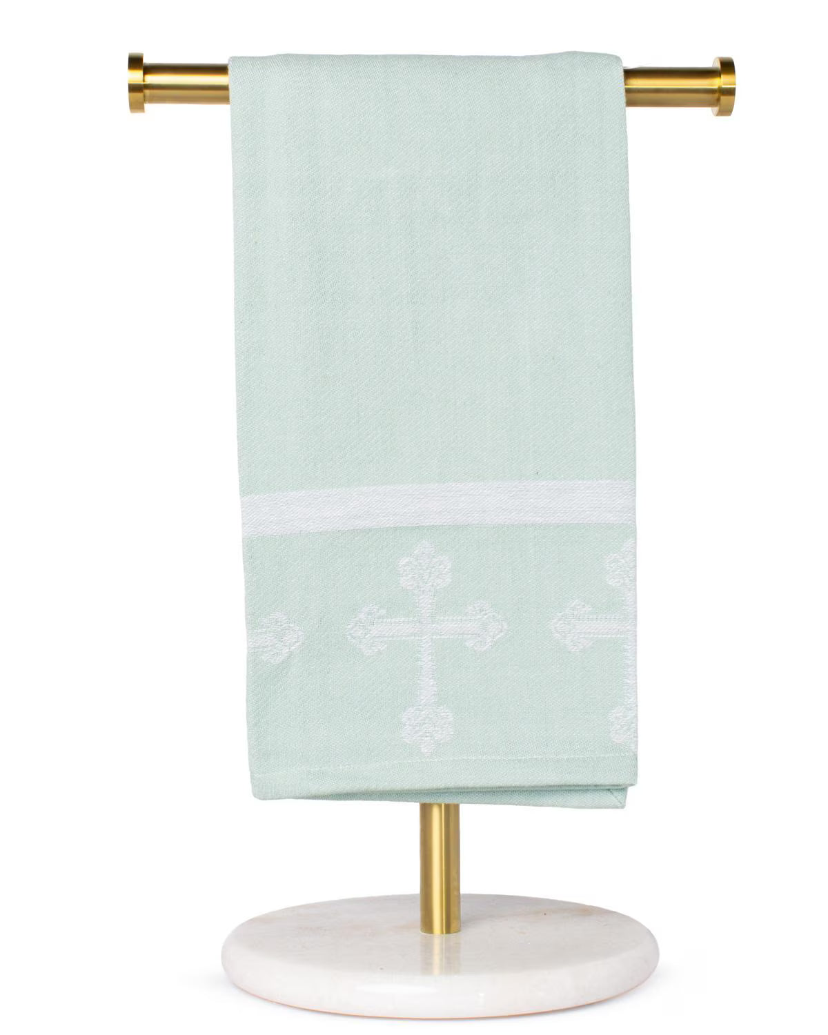 Light green towel with white cross design on a gold towel rack against a white background
