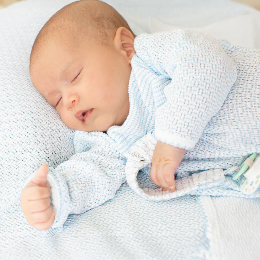 Newborn baby sleeping peacefully wrapped in a blue blanket