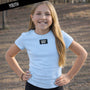 Young girl wearing a Light blue t-shirt with 'LULU MAC' logo outdoors.