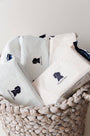 White pillows with a logo in a woven basket on a light background