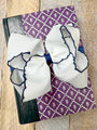 Large white bows with blue accents on a purple patterned fabric background.