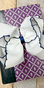 Large white bows with blue accents on a purple patterned fabric background.