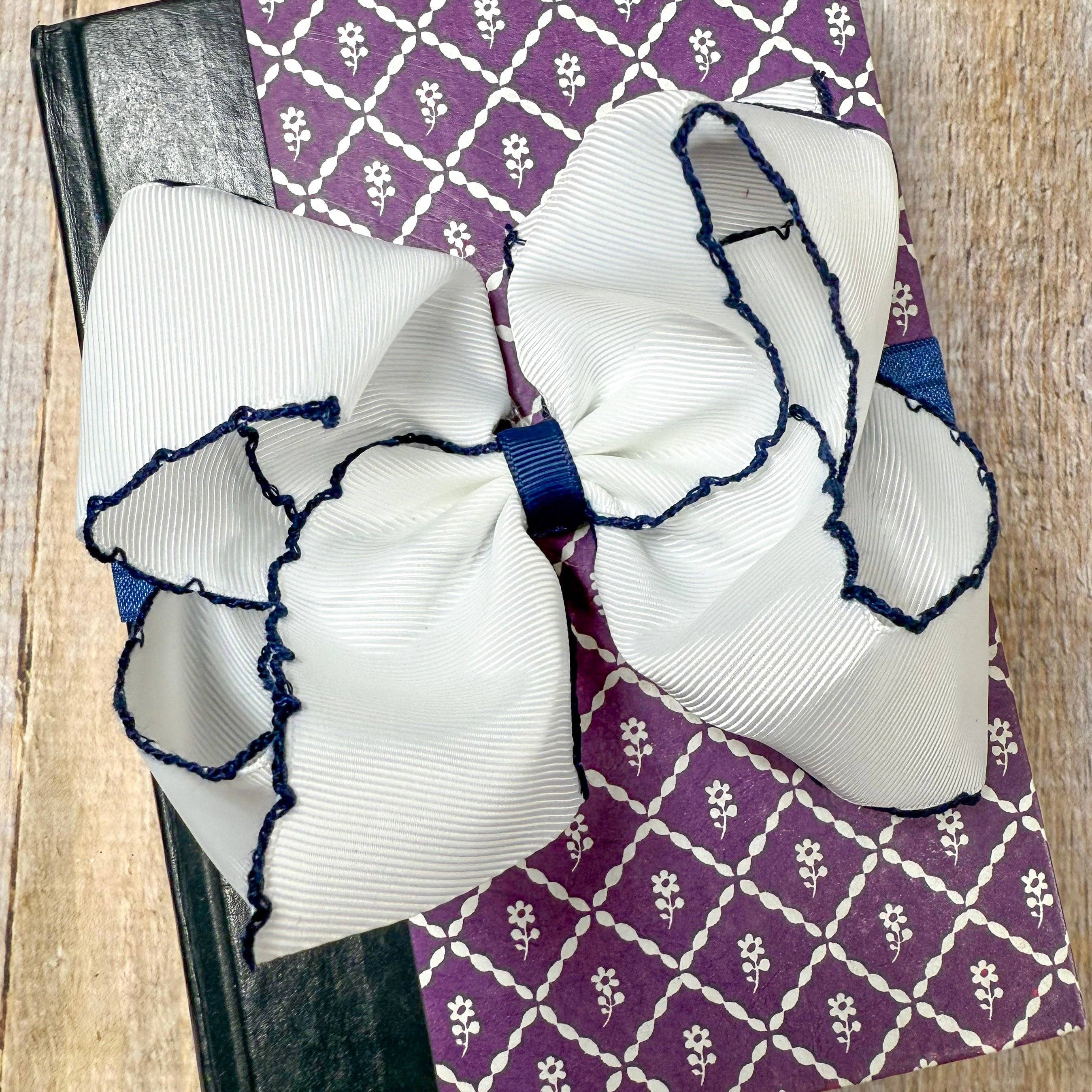 Large white bows with blue accents on a purple patterned fabric background.