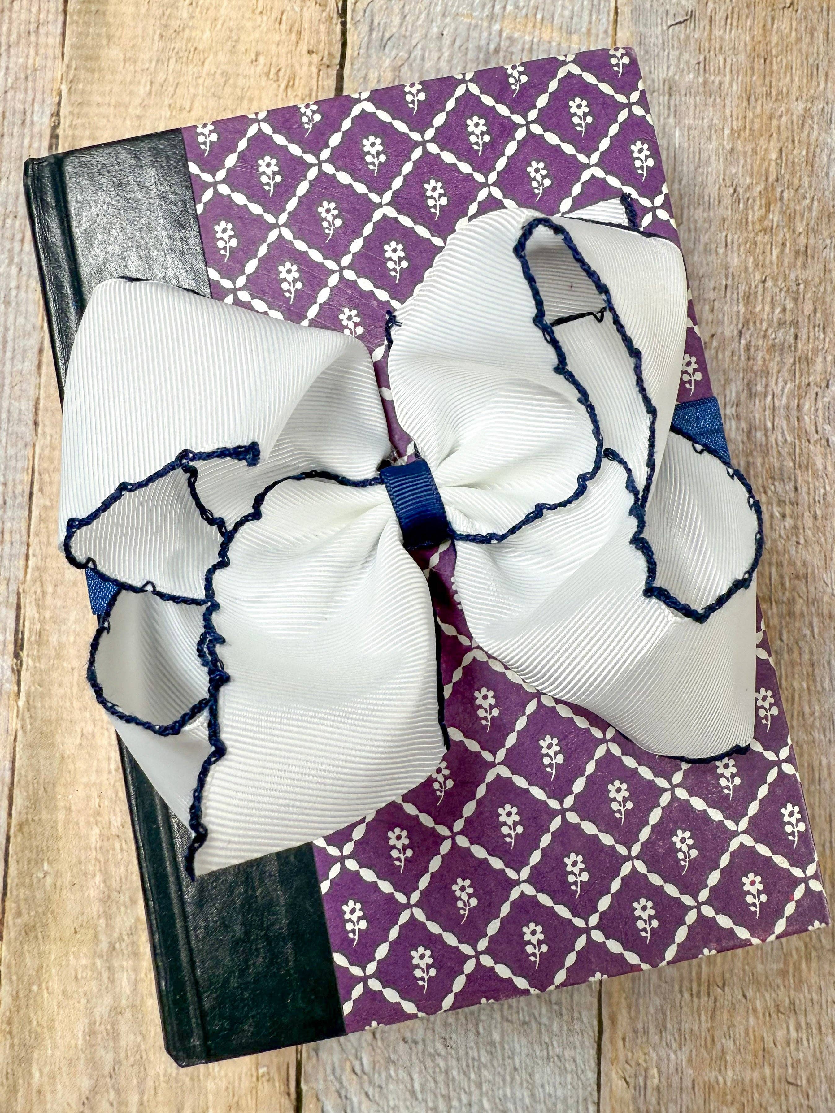 Large white bows with blue accents on a purple patterned fabric background.
