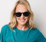 Woman wearing sunglasses and a teal shirt against a plain background