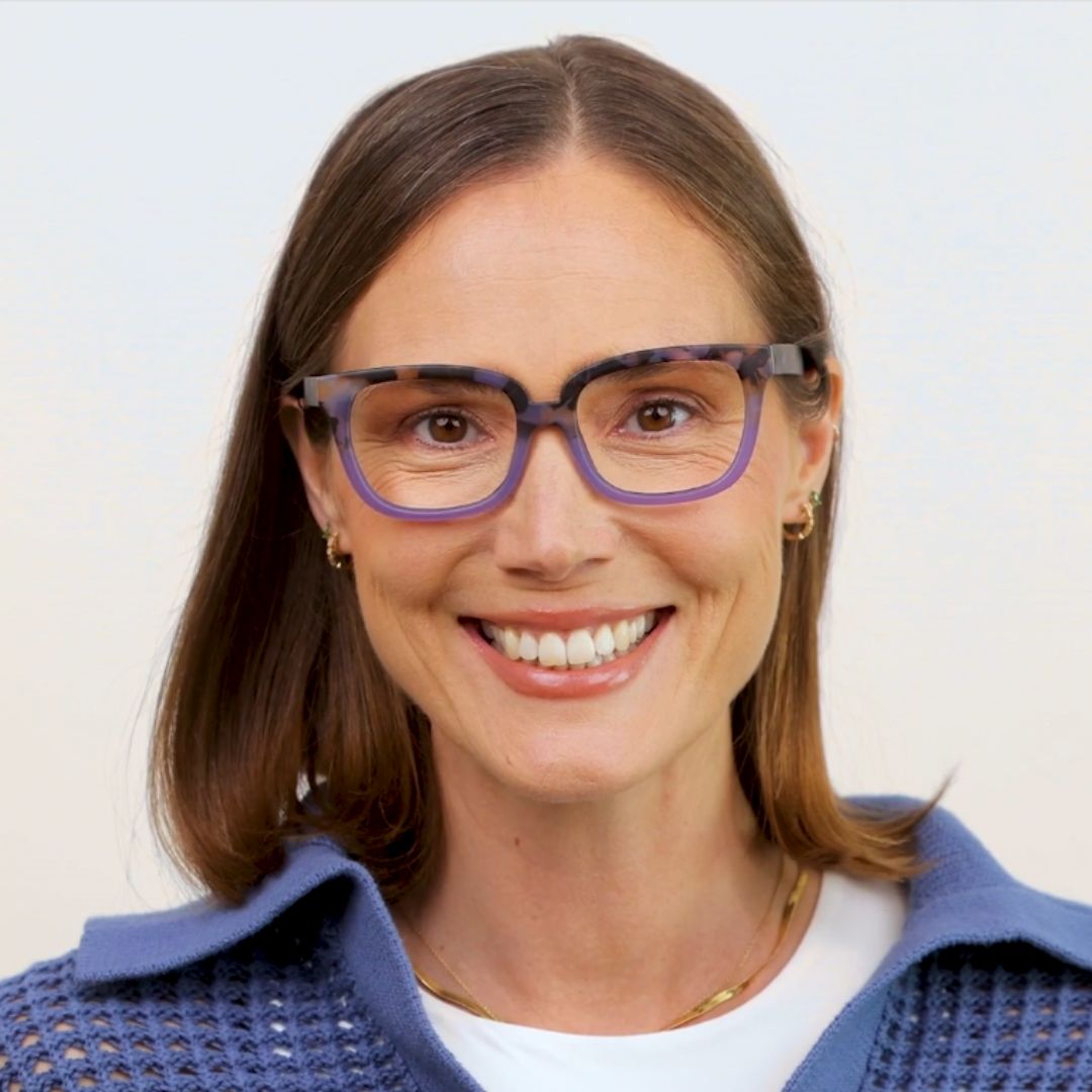 Woman wearing purple glasses with a light background