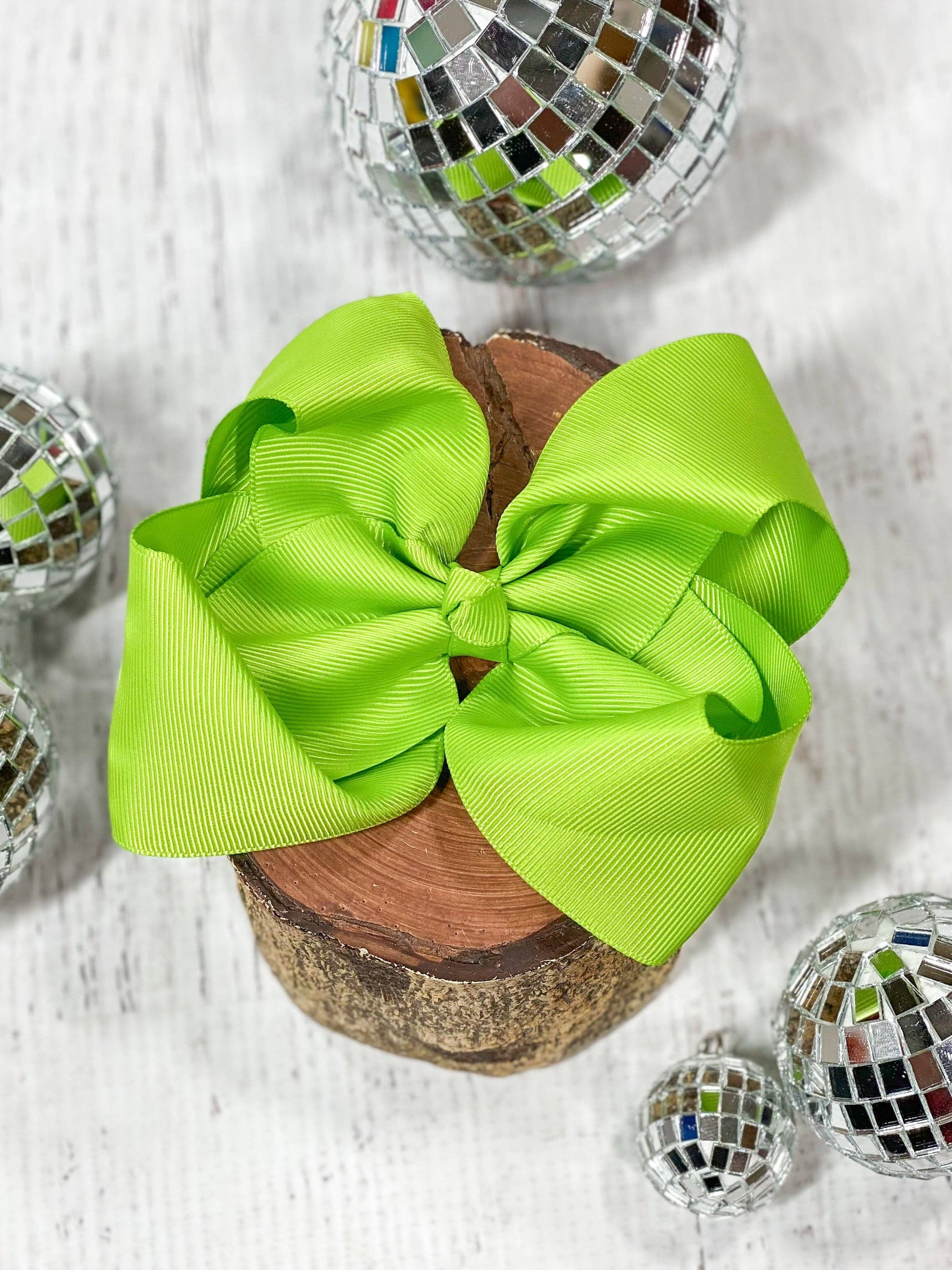 Large green bow on a wooden block with disco balls in the background