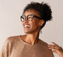 Woman wearing glasses and a sparkly top against a plain background