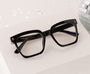 Black glasses on a white surface with a disco ball in the background