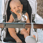 Baby in stroller with pacifier held by a linen clip attached to clothing