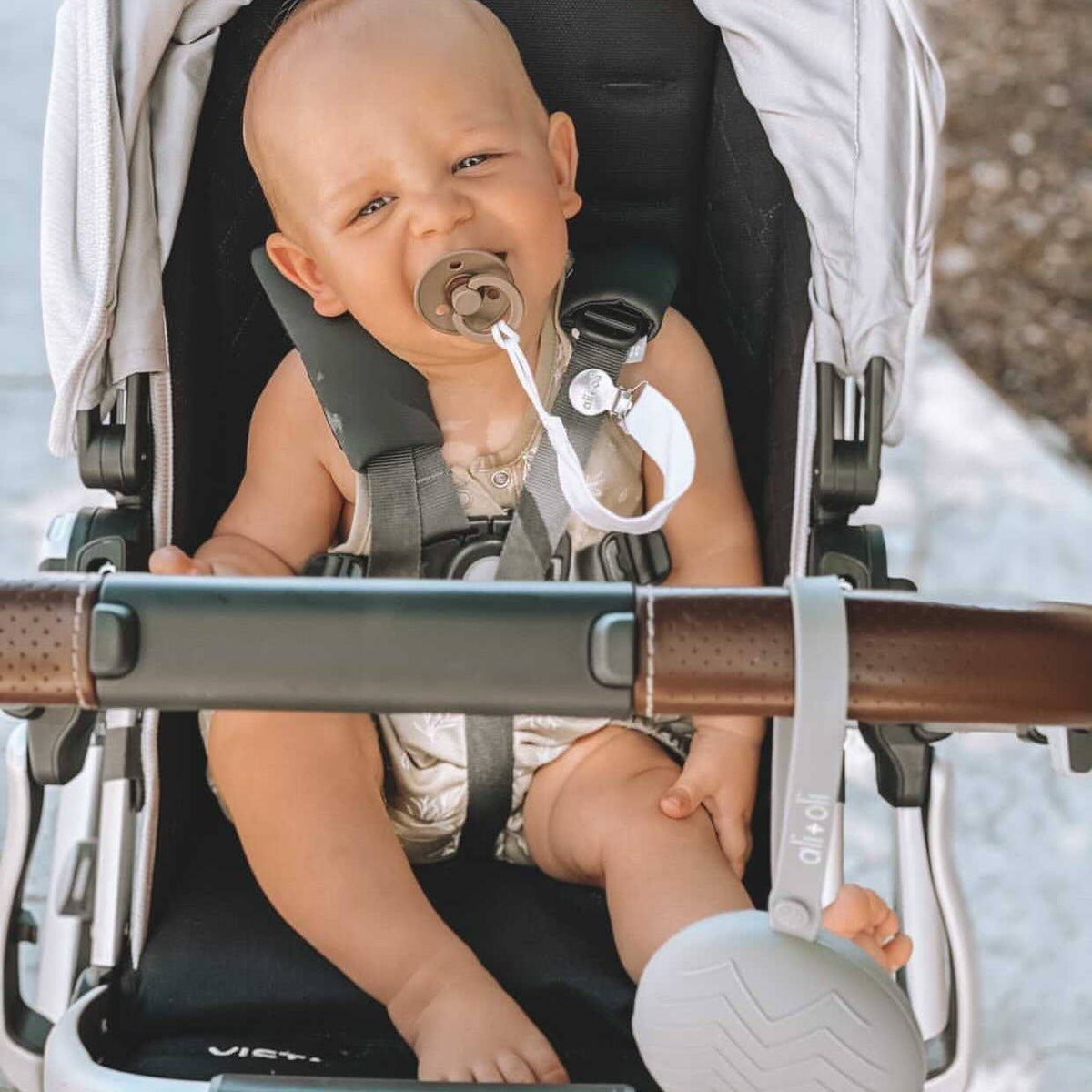 Baby in stroller with pacifier held by a linen clip attached to clothing