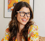 Woman wearing glasses and a colorful floral shirt in a home setting