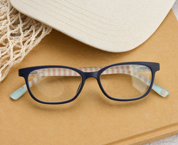 Blue eyeglasses on a textured surface with a hat in the background