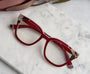Red eyeglasses with tortoiseshell accents on a marble surface