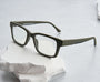 Green eyeglasses on a white stone surface with a light gray background