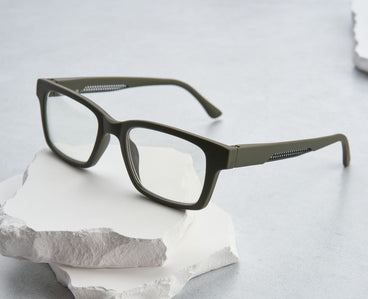 Green eyeglasses on a white stone surface with a light gray background