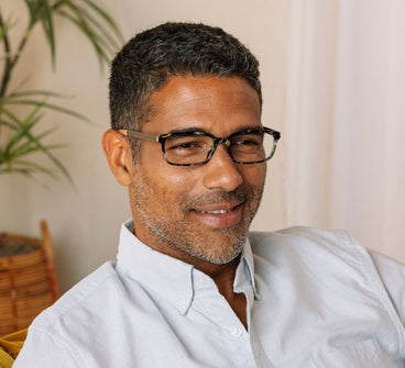 Man wearing glasses and a light shirt in an indoor setting