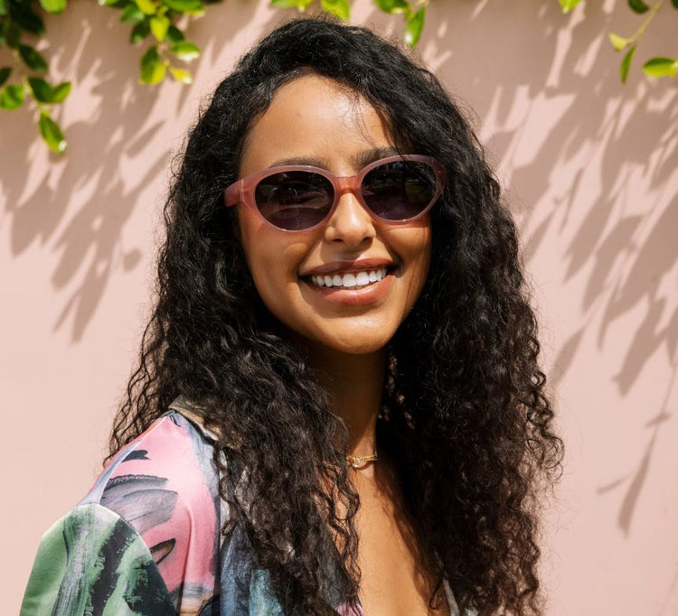 Woman wearing sunglasses with a pink background