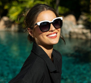 Woman wearing sunglasses with a scenic background of water and rocks