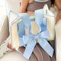 Person holding a striped bag with a large blue bow