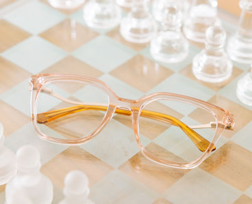 blush Clear cat-eye glasses on a checkard background