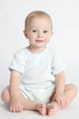 Baby wearing a blue textured romper with blue trim on a light gray background