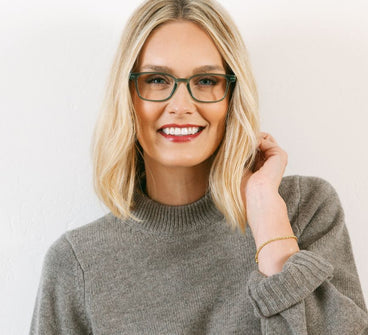 Woman wearing glasses and a gray sweater against a white background