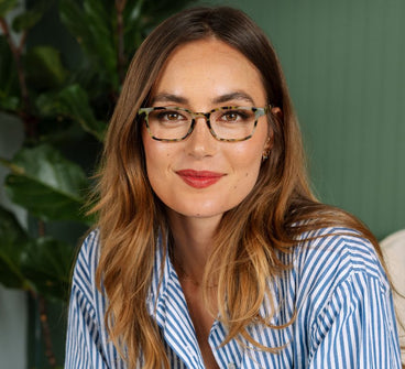 Woman wearing glasses and a striped shirt with a green background