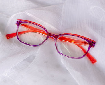 Orange and purple eyeglasses on a white fabric background