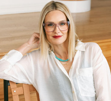 Woman wearing glasses and a white shirt with a blurred background