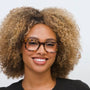 Woman with curly hair wearing glasses against a white background