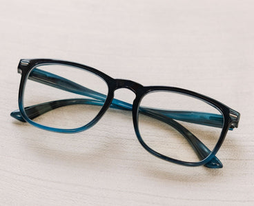Blue eyeglasses on a light wooden surface
