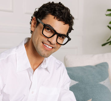 Man wearing glasses and a white shirt with a light background