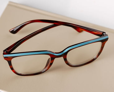 Eyeglasses with tortoiseshell frame and blue accents on a beige surface