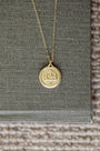 Gold necklace with a round pendant on a textured surface